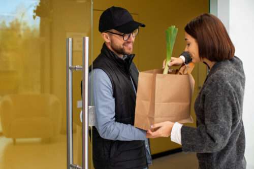 eine Frau überprüft die Produkte, die vom Lieferboten geliefert werden